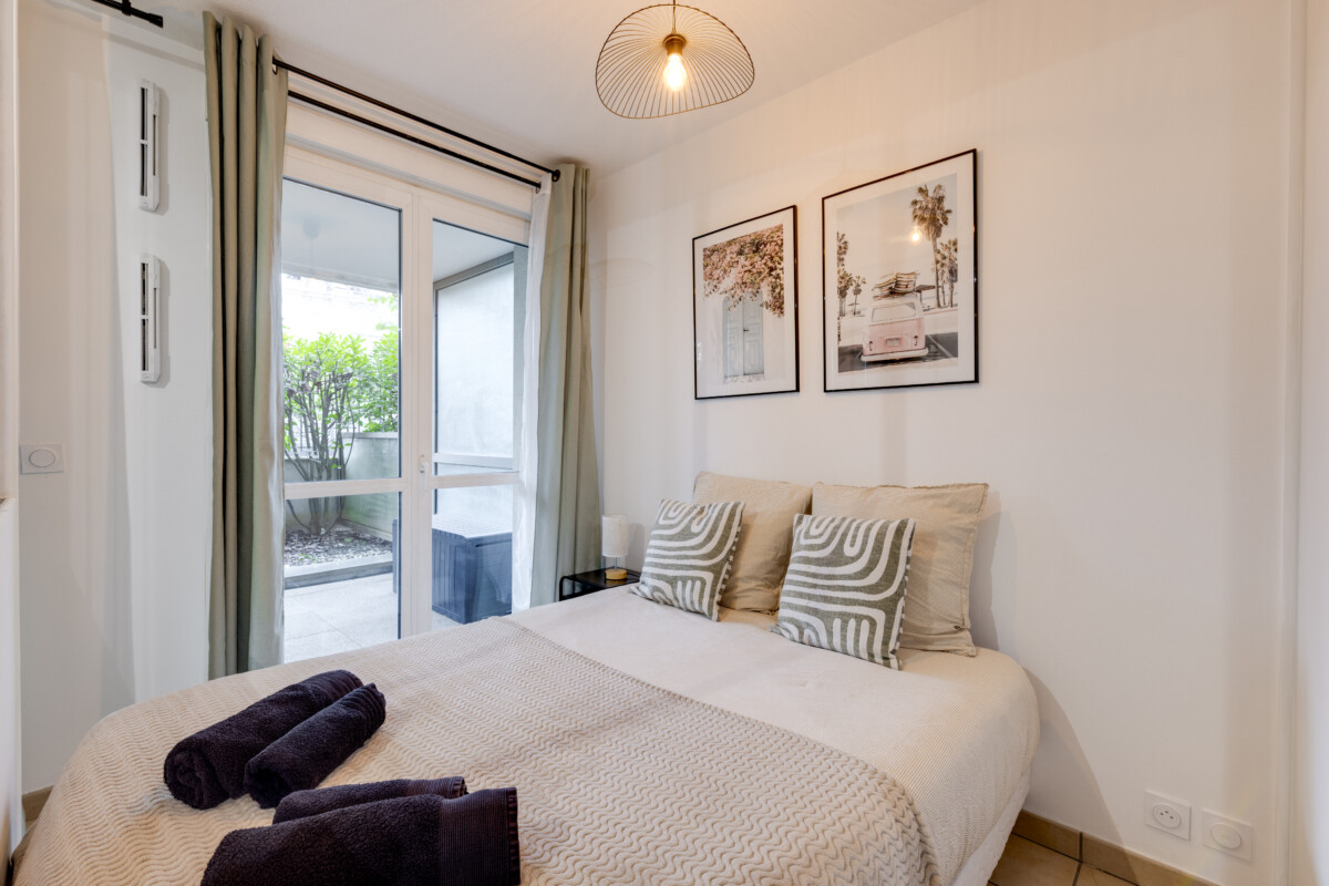 Chambre moderne avec lit double, décoration chaleureuse, et accès direct à une terrasse végétalisée à Brive-la-Gaillarde.