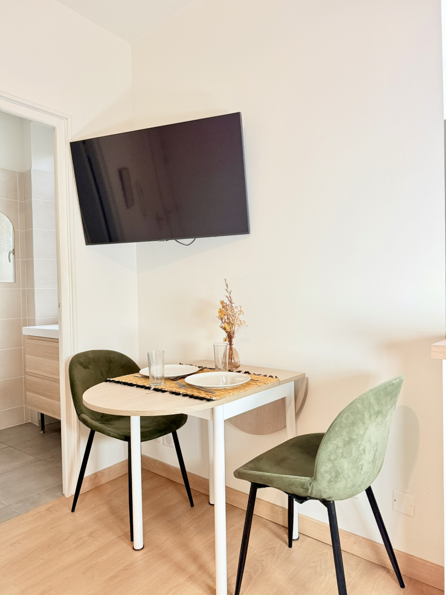 Coin repas pour deux avec télévision murale dans appartement à Brive-la-Gaillarde – Appart’Cosy
