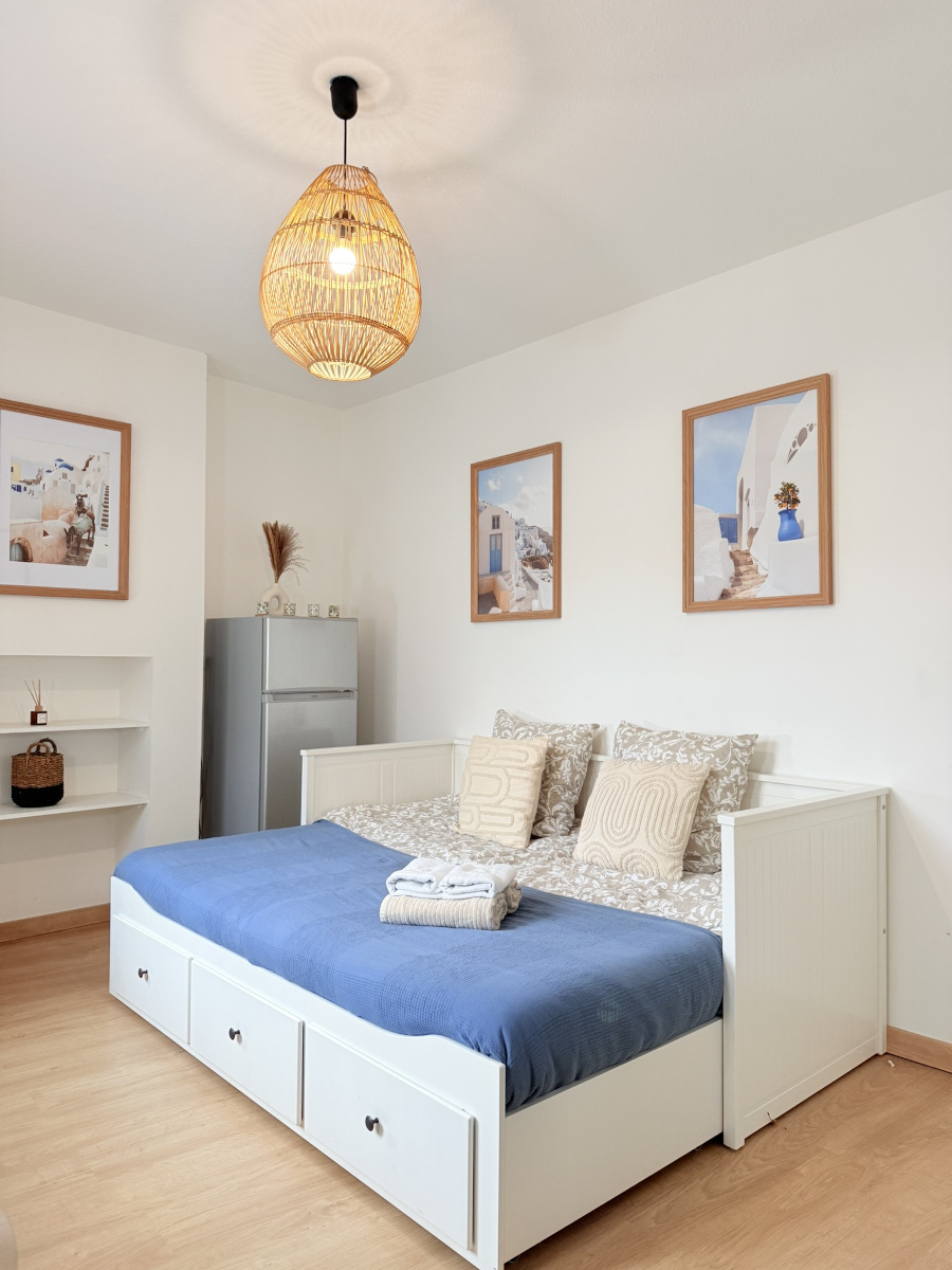 Coin nuit confortable à Sarlat avec lit double, éclairage chaleureux et décoration soignée – Appart’Cosy