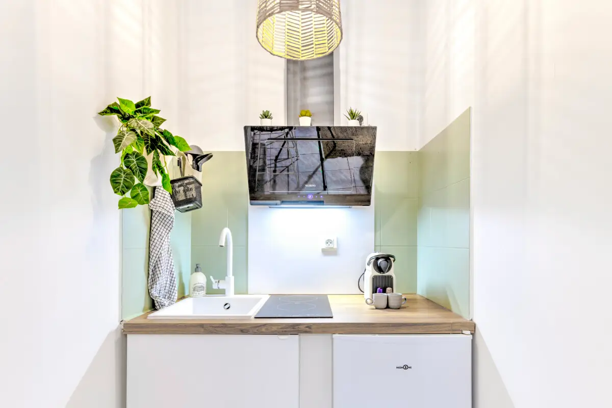 Coin cuisine équipé dans studio à Sarlat avec plaques de cuisson, machine à café et rangements – Appart’Cosy Le Papucie