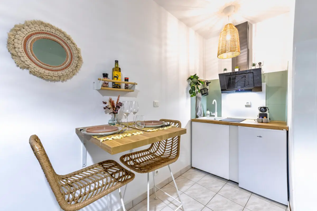 Coin repas avec table en bois et cuisine équipée dans studio à Sarlat – Appart’Cosy Le Papucie