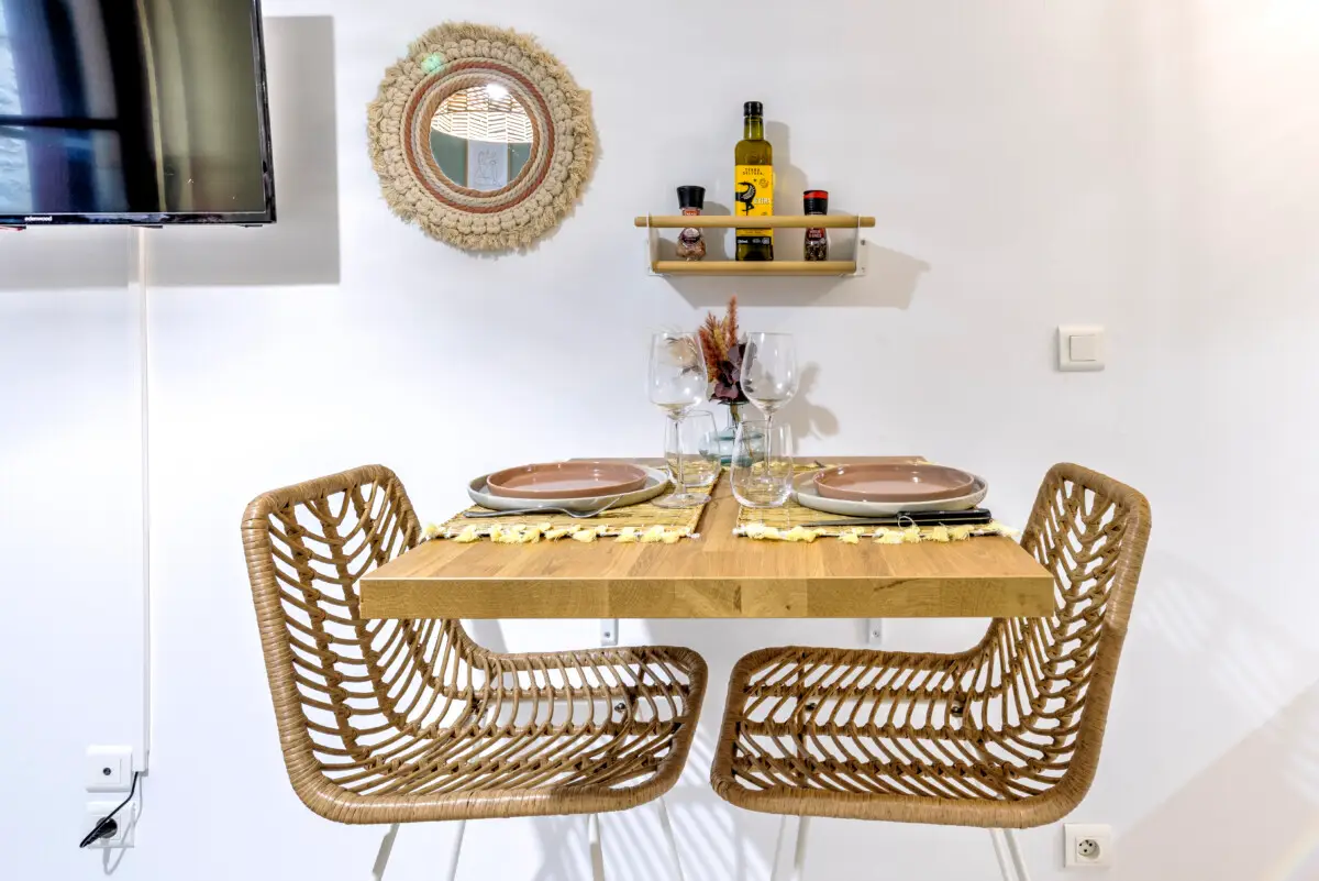 Coin repas pour deux dans studio à Sarlat avec table en bois et chaises en rotin – Appart’Cosy Le Papucie
